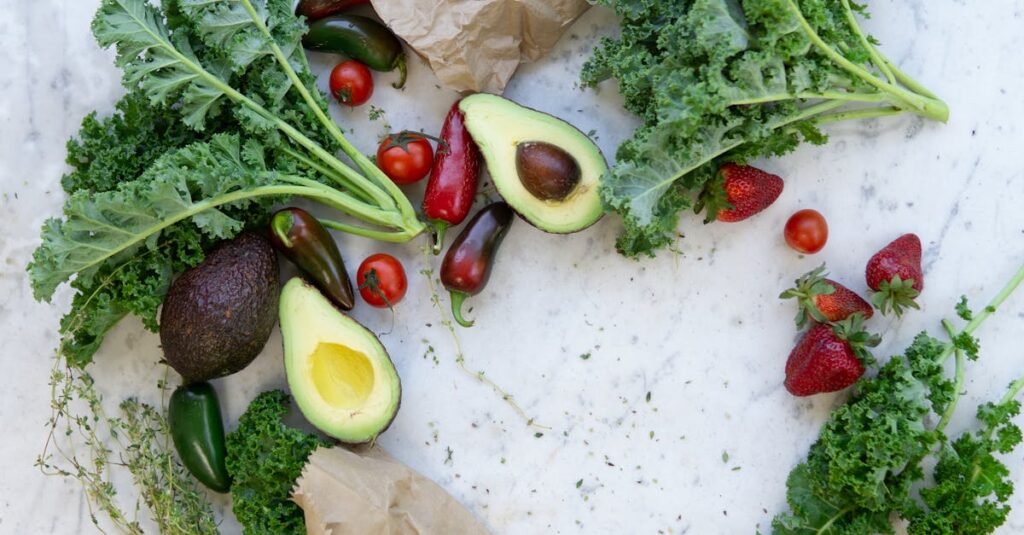 pexels-photo-1660027-1660027 Top view of fresh avocados, kale, tomatoes, and peppers arranged on a marble surface.